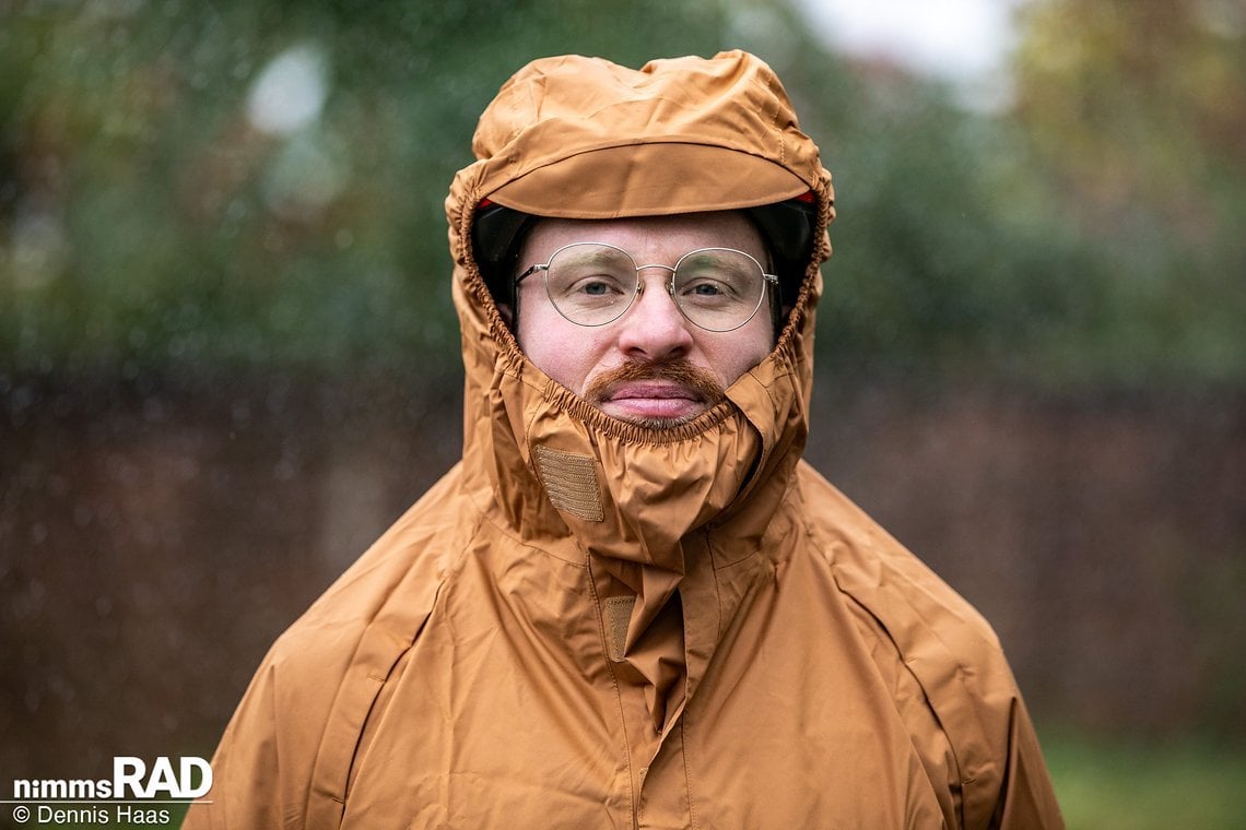 Eine große Kapuze bietet Platz für den behelmten Kopf, ein Gummizug hält die Halspartie trocken und die kleine Krempe vorn hilft ebenfalls, nicht zu viel Wasser abzubekommen.